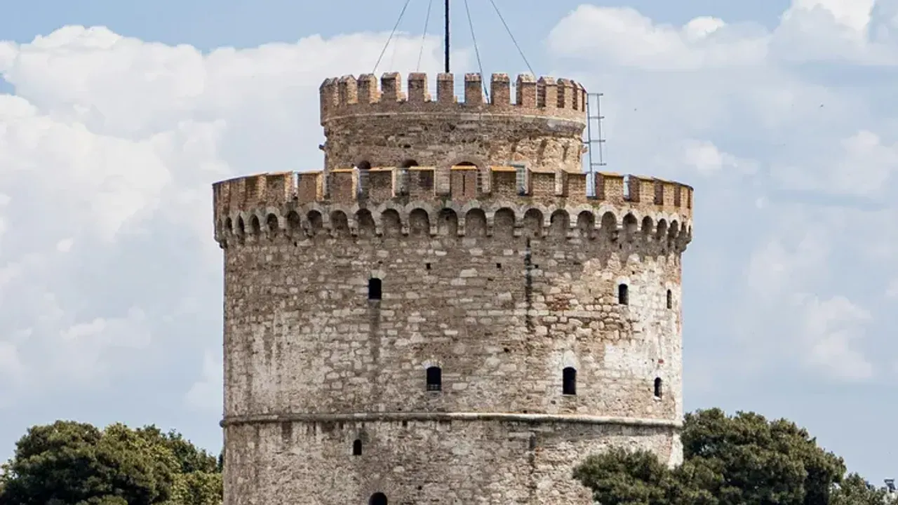 The cylindrical White Tower of Thessaloniki on the waterfront against a blue sky