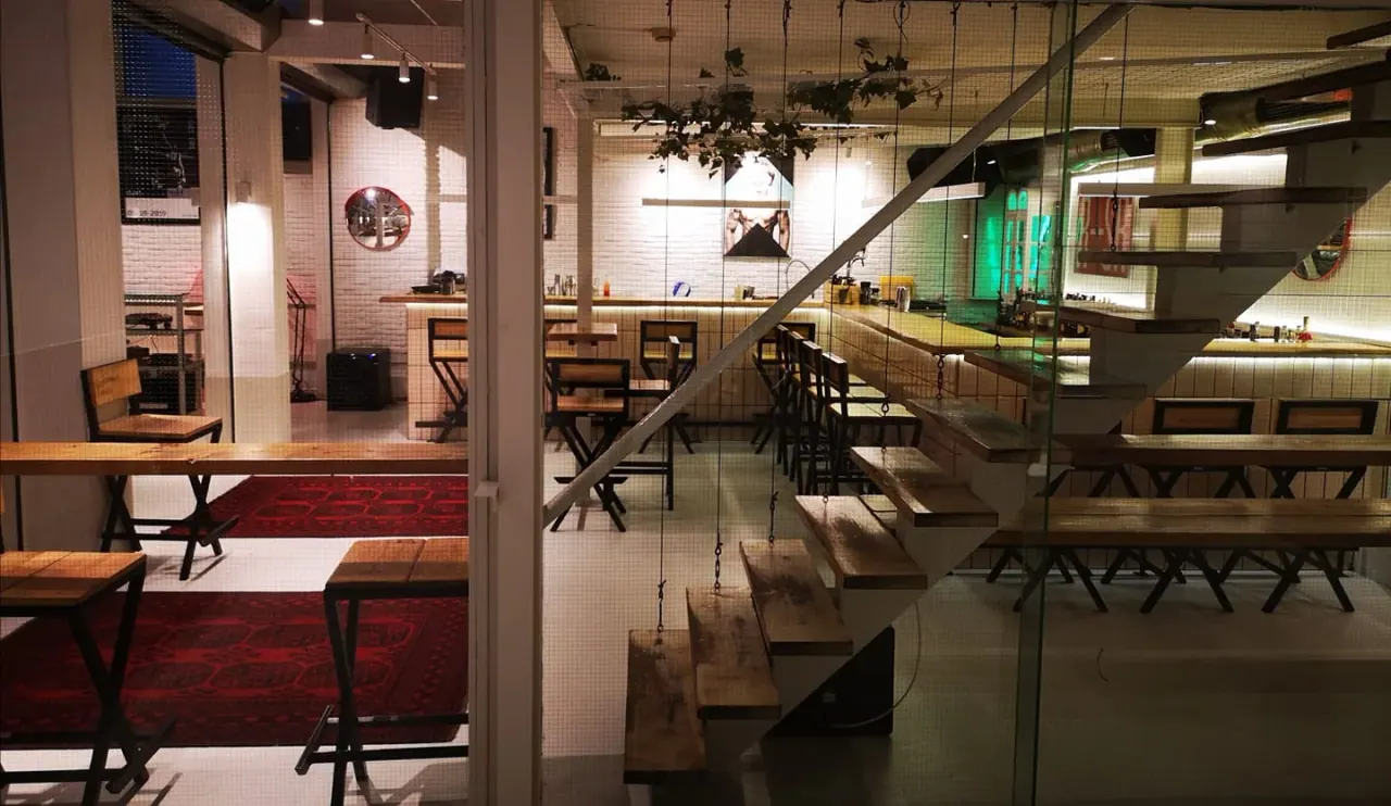 The white-tiled, minimalist interior and floating staircase of Bord de l'Eau drinkroom on Egnatia, Thessaloniki
