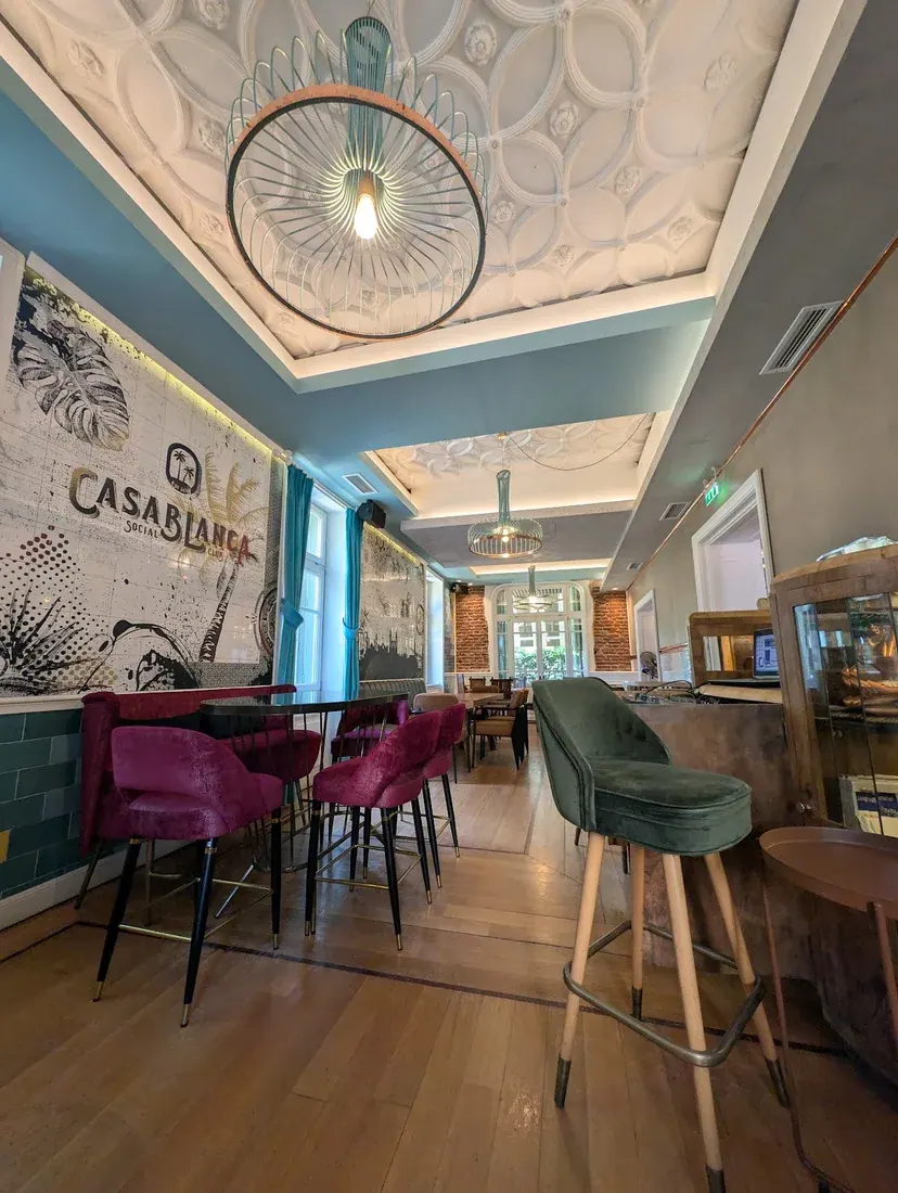 The ornate interior of Casablanca Social Club — stucco ceiling, velvet stools and a Casablanca mural — inside a historic Thessaloniki mansion