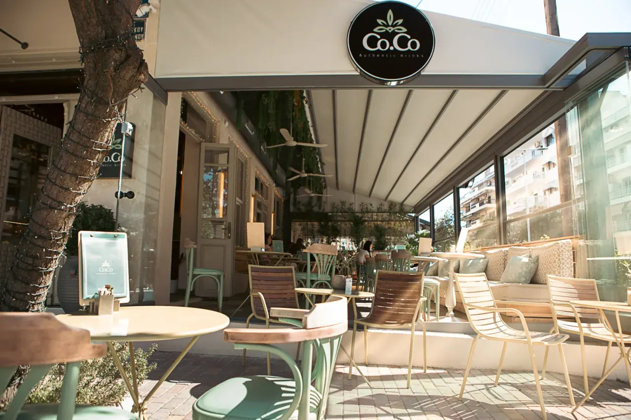 Leafy covered terrace with pale-green chairs at Co.Co Authentic Drinks cocktail bar in Thessaloniki