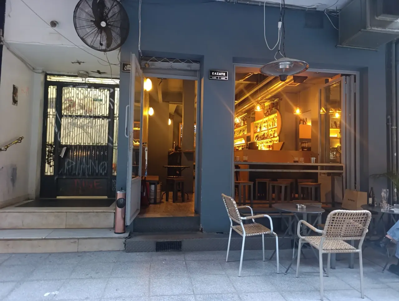 The warm, bottle-lined bar of Elxate seen from its open frontage on Isavron street, Thessaloniki