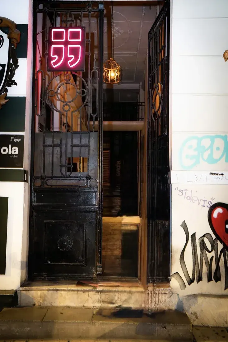 The black door and red neon sign of Enola bar-club in the Valaoritou district of Thessaloniki at night