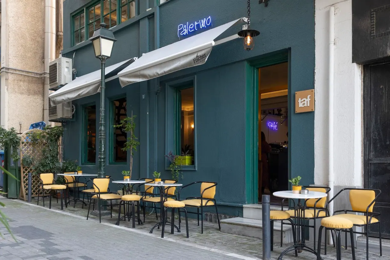 The teal facade and blue neon sign of Palermo café-bar with pavement tables near Navarinou Square, Thessaloniki