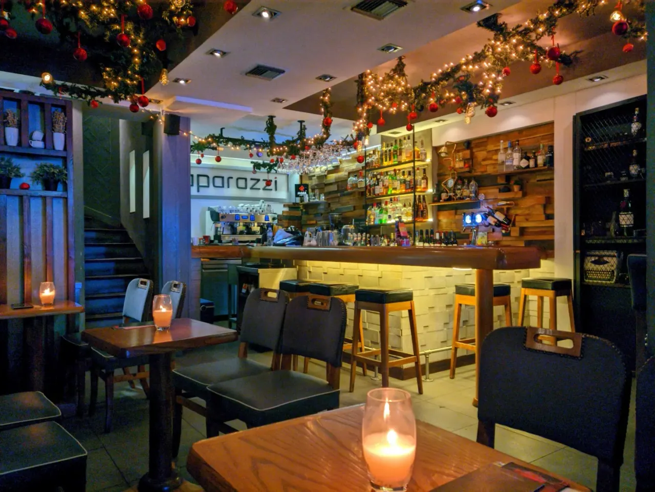 The warm wood-and-brick bar of Paparazzi all-day café-bar strung with festive lights on Agias Sofias, Thessaloniki