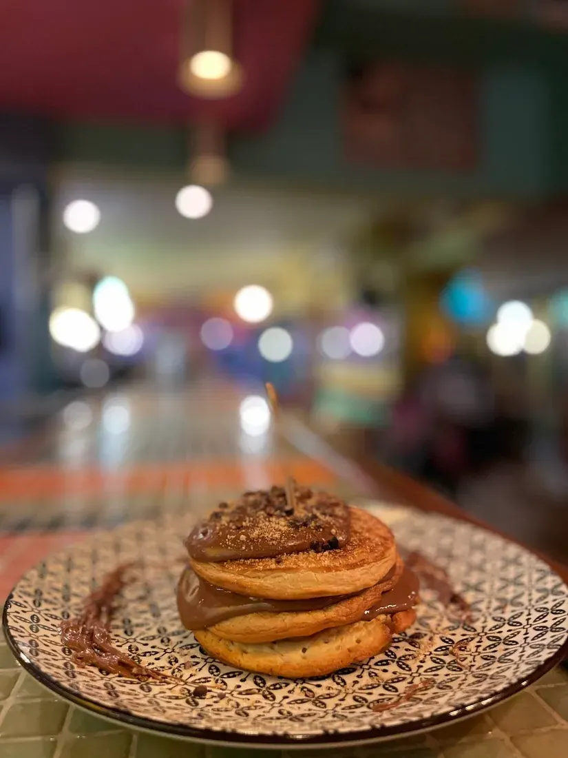 A stack of pancakes on a patterned plate inside the colourful, retro Pastaflora Darling café-bar in Thessaloniki