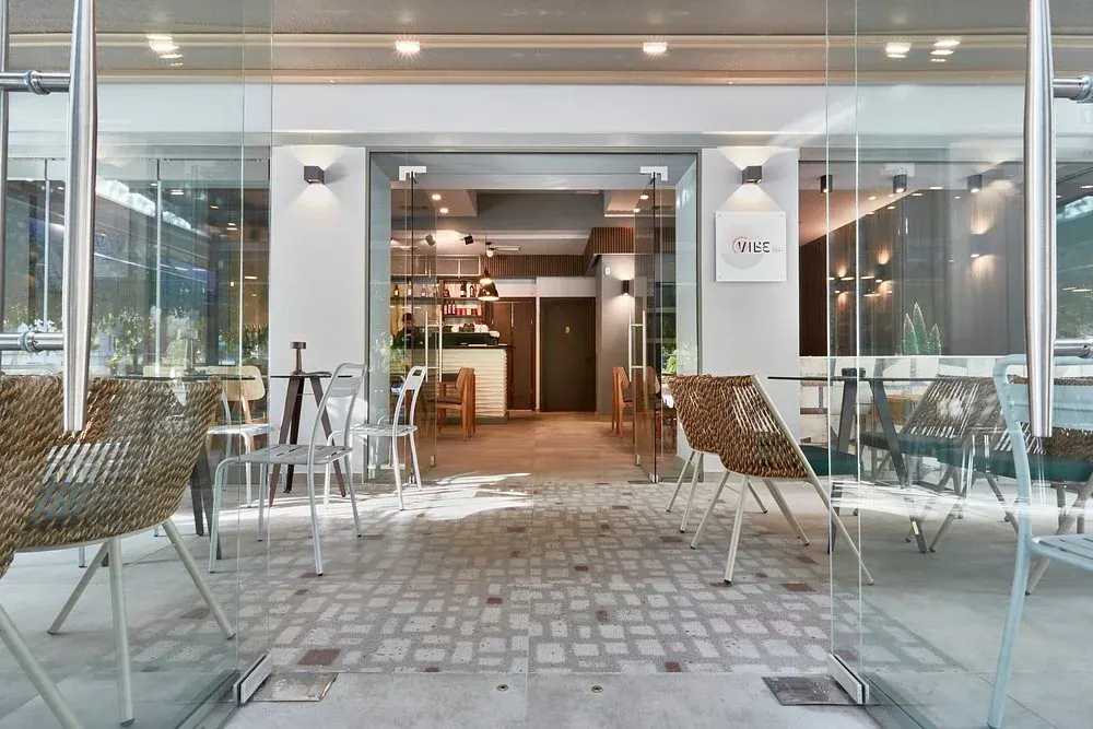 The glass-fronted, minimalist interior and woven-chair terrace of Vibe all-day bar near Navarinou, Thessaloniki